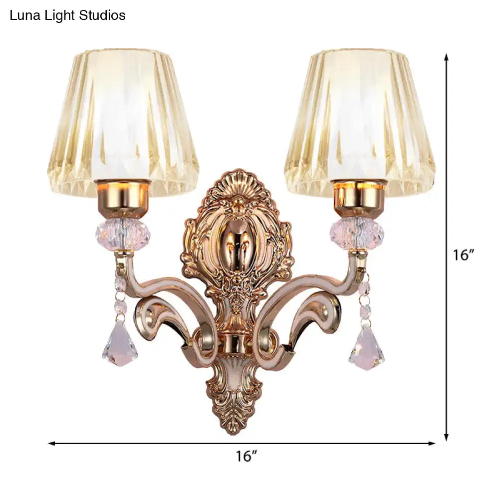 Vintage brass wall lamp with gold-toned ornate design, two fluted amber glass shades, and pink crystal accents