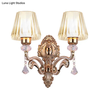 Vintage brass wall lamp with gold-toned ornate design and fluted amber glass shades featuring dangling pink crystals