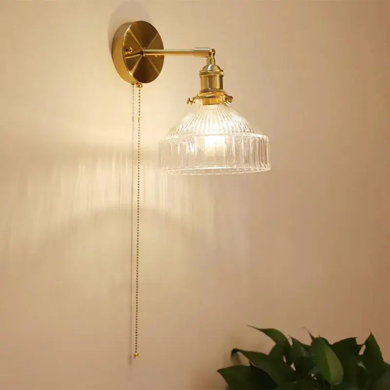 Vintage brass wall lamp with brass finish and ribbed clear glass shade with attached pull chain for living room use