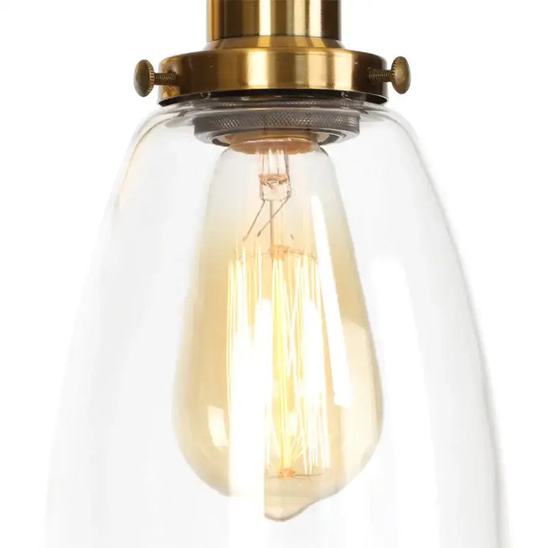 Vintage brass wall light fixture with warm-toned edison bulb encased in clear glass dome for bedroom use
