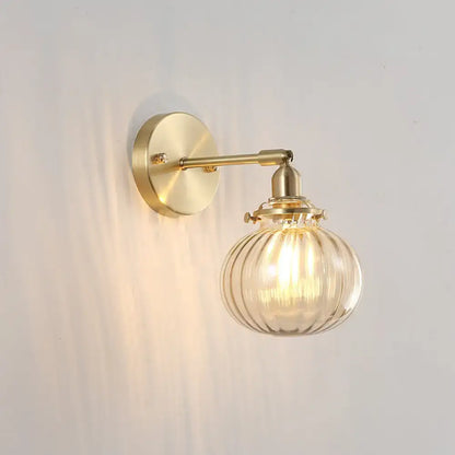 Vintage brass wall light with champagne clear ribbed glass shade and exposed filament bulb for bedroom use