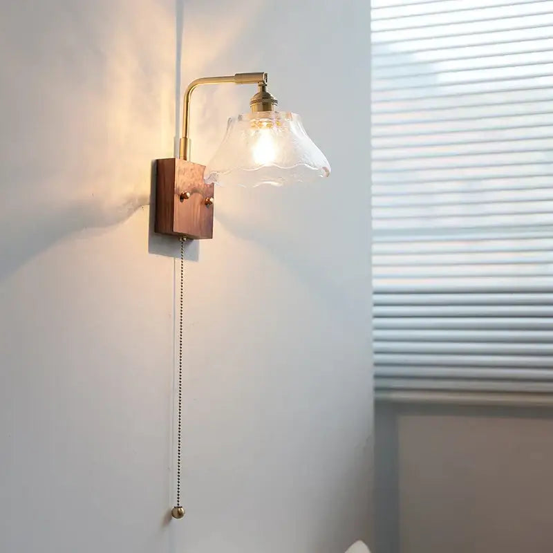 Vintage brass wall light with warm-toned brass, clear glass scalloped shade, and wooden base decorbites clear glass design