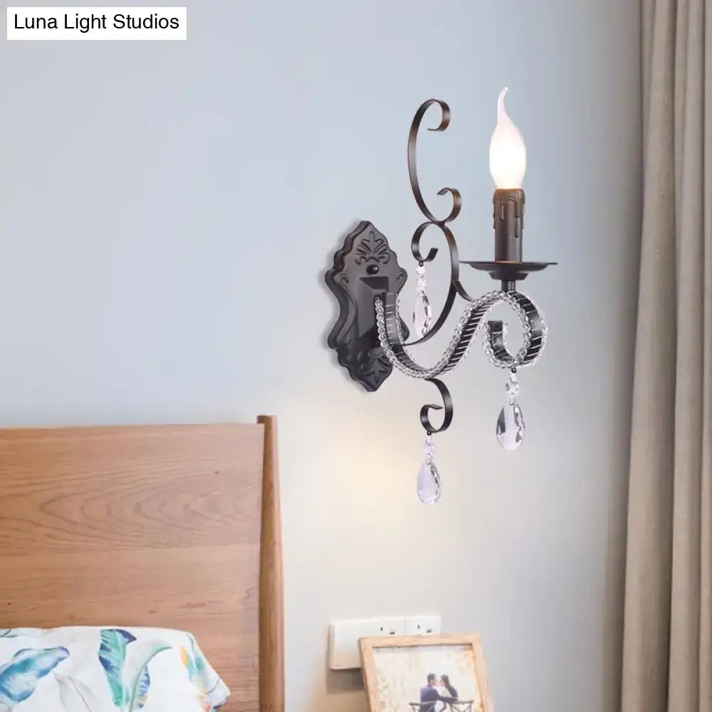 Black wrought iron wall mounted lamp with crystal droplets and candle-style bulb for vintage living room ambiance