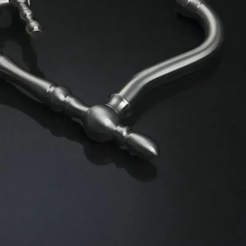 Vintage brushed nickel kitchen faucet with swivel spout and decorative silver-toned necklace chain featuring ornate design