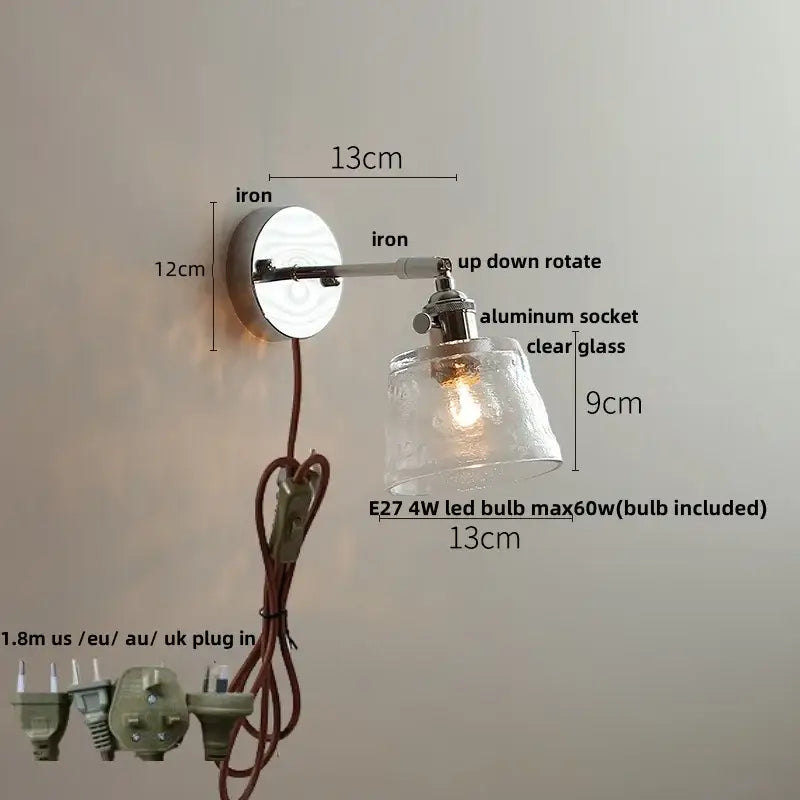 A vintage brushed nickel led wall light with polished iron arm and clear glass shade for bedroom use