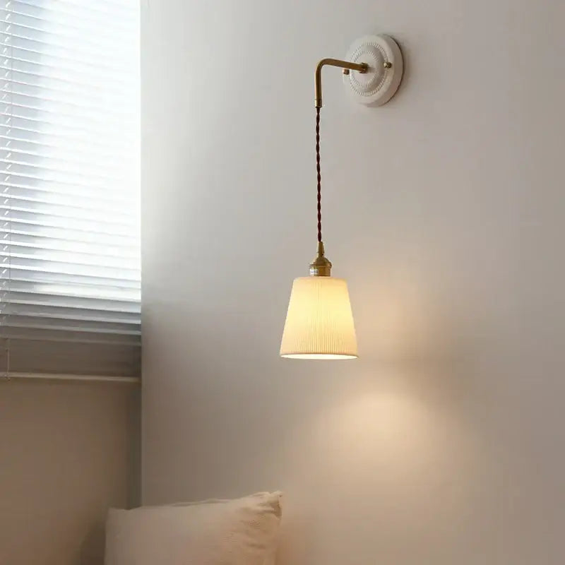 A warm-toned brass vintage ceramic wall sconce with adjustable led light and pleated off-white fabric shade decorbites adjustable led