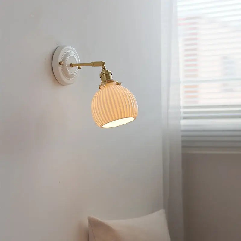 Vintage wall sconce light with cream ribbed glass shade and brass-finished metal arms for bedroom pull chain use