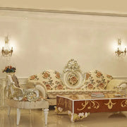 Cream-colored floral sofa with ornate silver-gold detailing complements vintage champagne finish wall light with clear crystal