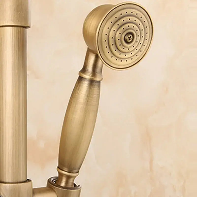 Antique brass handheld showerhead with circular spray face and ridged handle paired with vintage shower hand holder