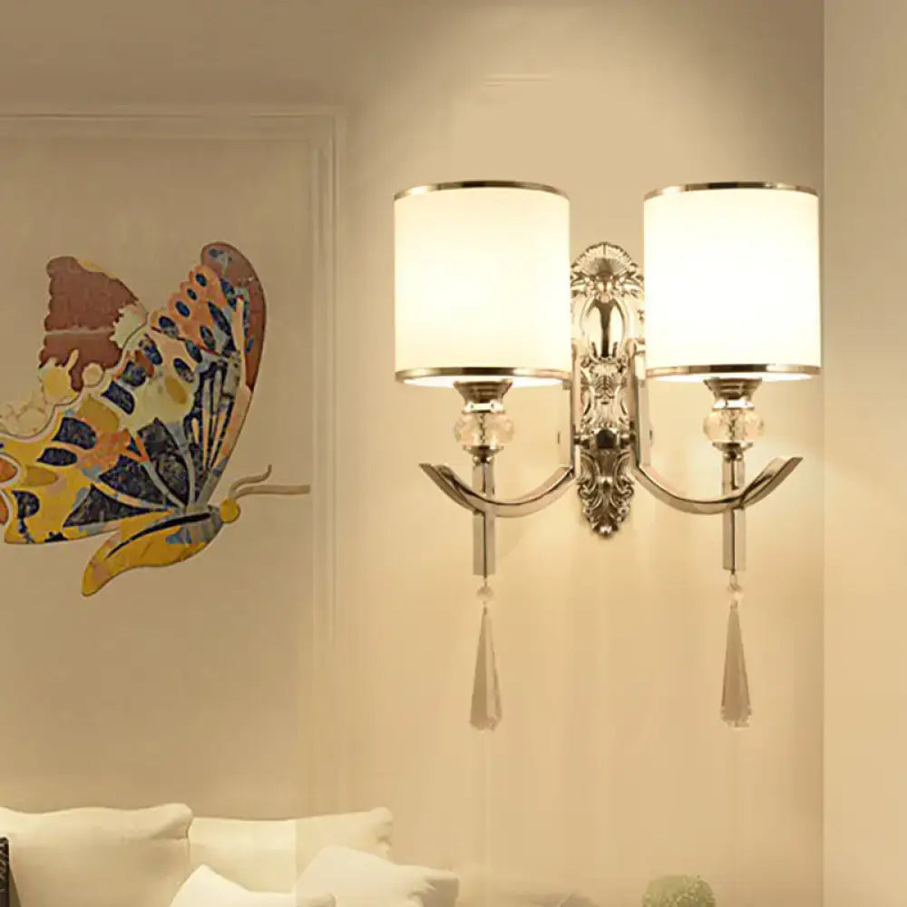 Vintage chrome wall sconce with carved backplate featuring silver ornate design, two fabric shades, and crystal tassels