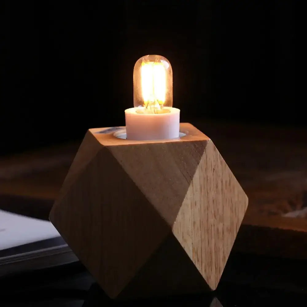 A warm glowing vintage clear glass led filament night bulb sits in a light wood geometric base decorbites dimmable t20