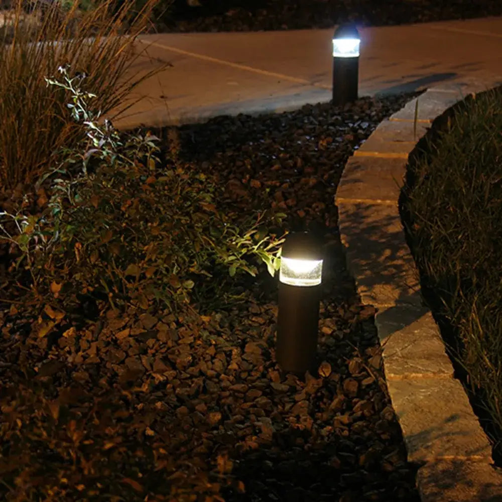 Black cylindrical pathway lights with frosted glass diffusers emit warm white glow featuring decorbites dimmable t20 led filament night bulb