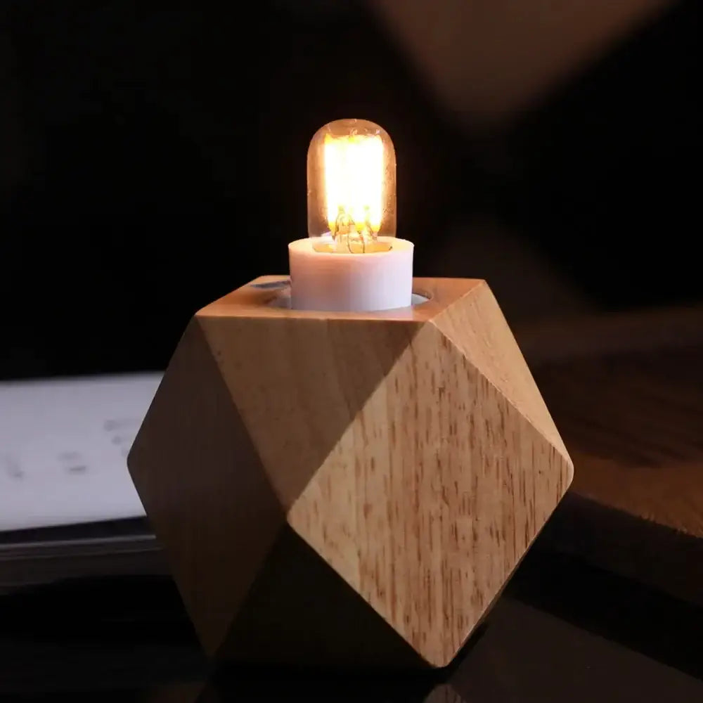 A warm glowing vintage clear glass led tubular bulb on a geometric wooden base with natural wood grain