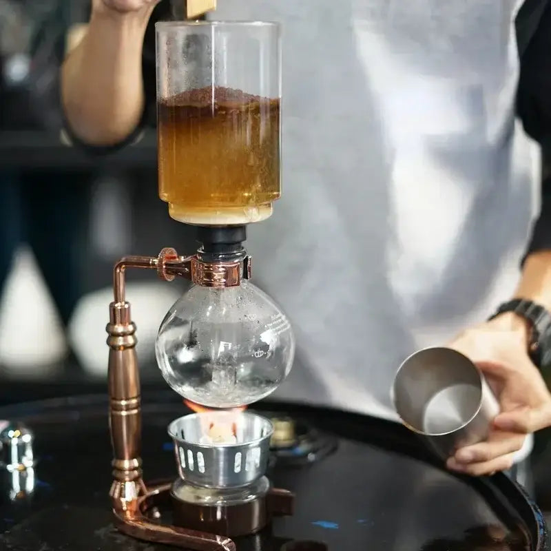 Vintage copper coffee jug siphon maker with clear glass upper chamber and lit burner for decorbites coffee jug use