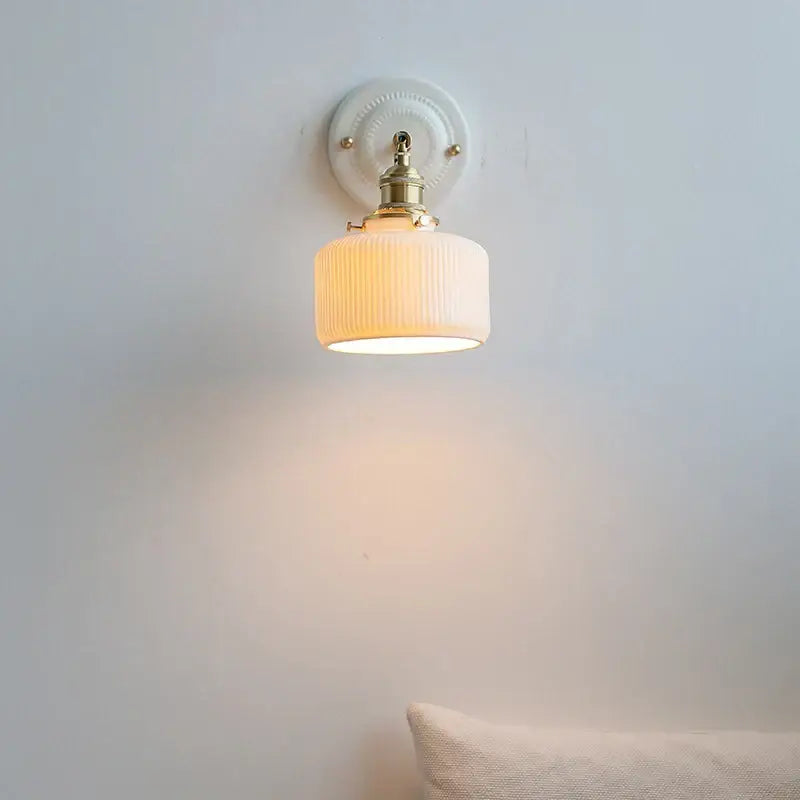 A warm cream ribbed glass ceramic led wall lamp with brass fixture on white plate for vintage bedroom decorbites ceramic led