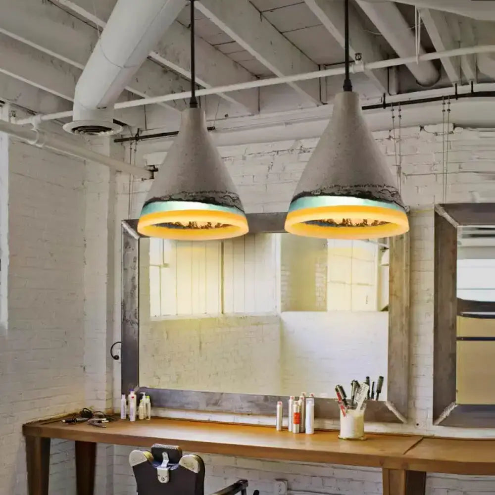 Concrete pendant light with textured grayish-white finish and yellow-gold illuminated rims in dark blue and light blue tones