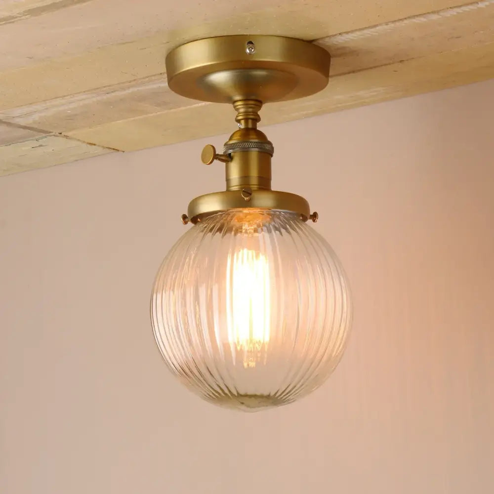 Vintage dark bronze semi flush mount ceiling light with a ribbed glass globe in brass finish for bedroom use