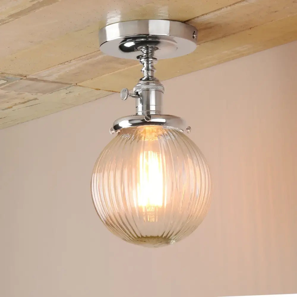 Vintage dark bronze semi flush mount ceiling light with ribbed glass globe and chrome metal fixture emitting warm glow