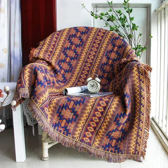 Cozy bohemian cotton plaid sofa throw blanket in warm orange and deep blue with geometric patterns and fringed edges