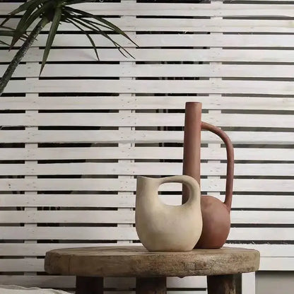 Two ceramic pitchers in beige matte and terracotta brown ceramic on a rustic table for decorbites geometric stoneware decor