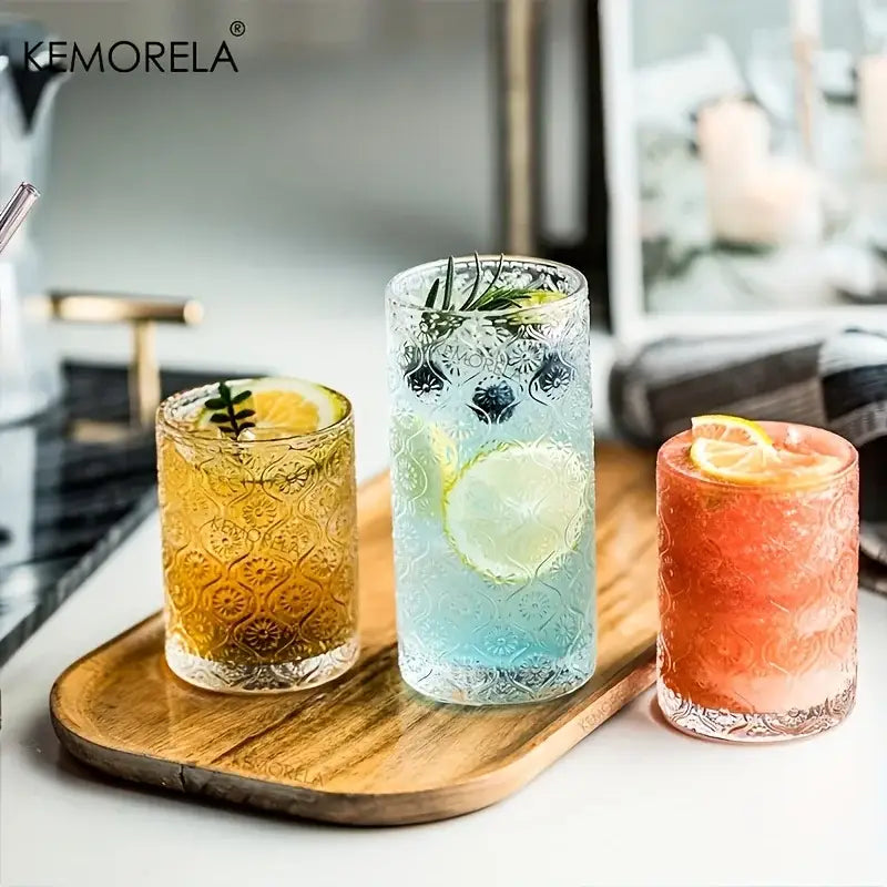 Three kemorela vintage glassware set tumblers embossed with floral patterns filled with colorful garnished beverages