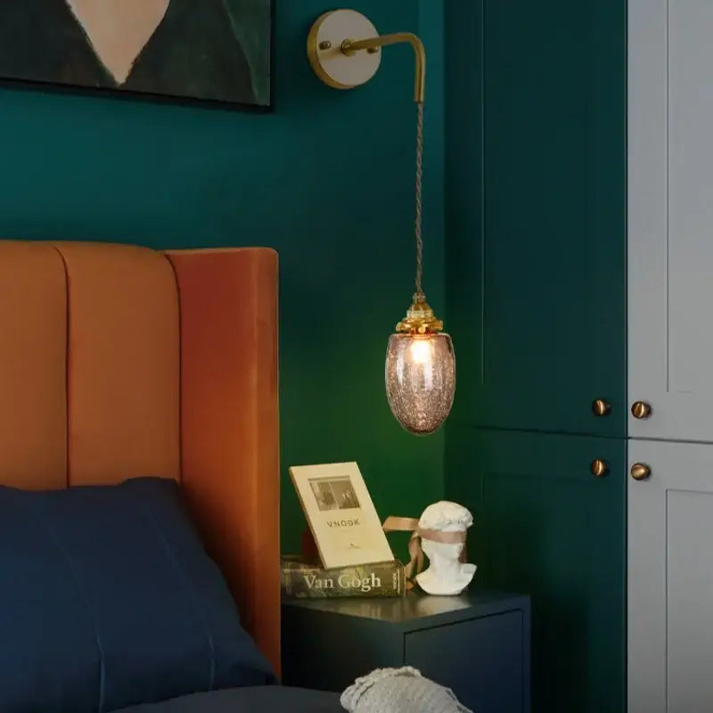 A brass-finished wall lamp with a dangling textured amber glass pendant for decorbites grey glass led bedroom lighting