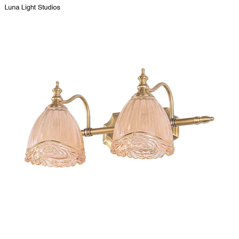 A pair of vintage floral wall sconces with amber glass shades and gold brass-finished metal arms for bedroom use