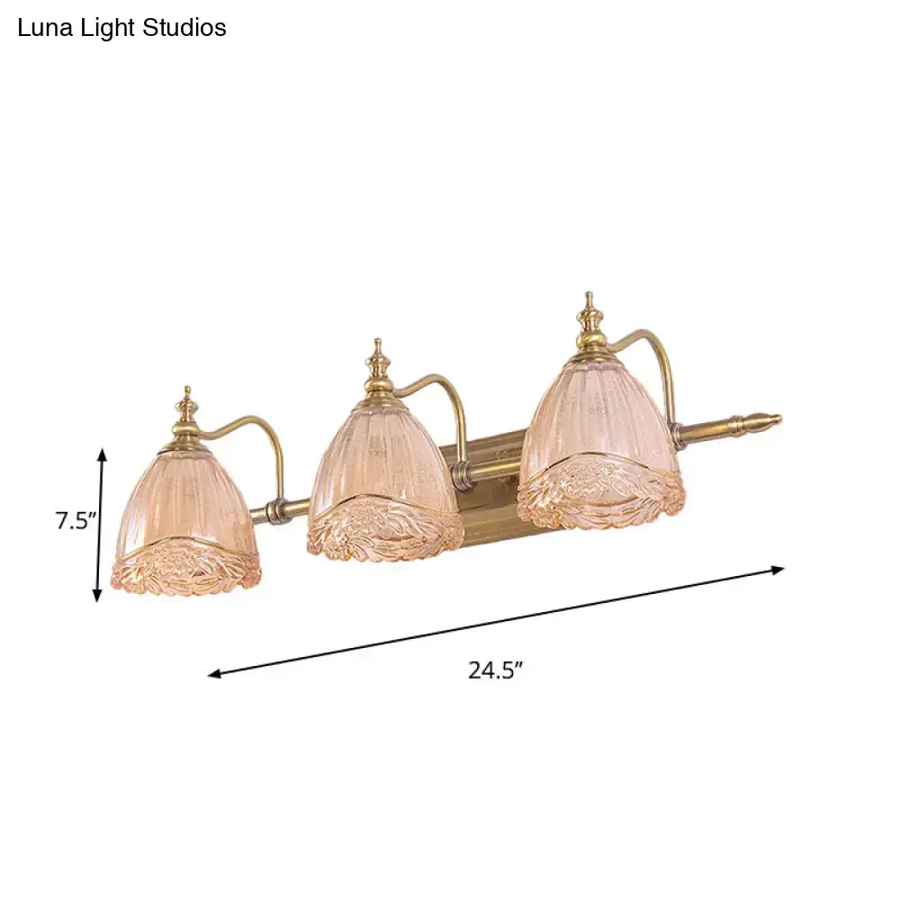 A three-light vintage brass vanity fixture with ornate amber glass floral shades for bedroom wall sconces