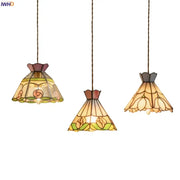 Three elegant tiffany-style pendant lights with colorful flower stained glass shades in warm amber green and rose hues for decorbites