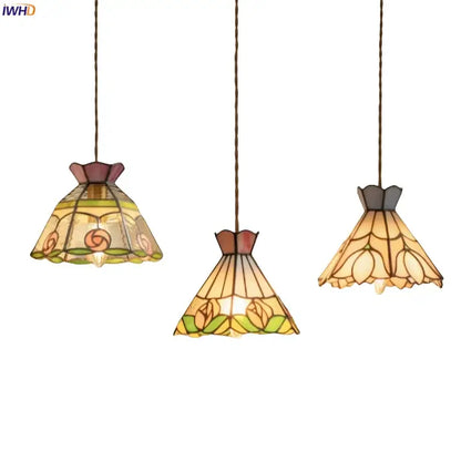 Three elegant tiffany-style pendant lights with colorful flower stained glass shades in warm amber green and rose hues for decorbites