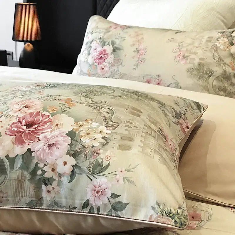 A cream-colored pillow sham with vintage flowers print featuring pink blossoms and satin trim in a bedding set