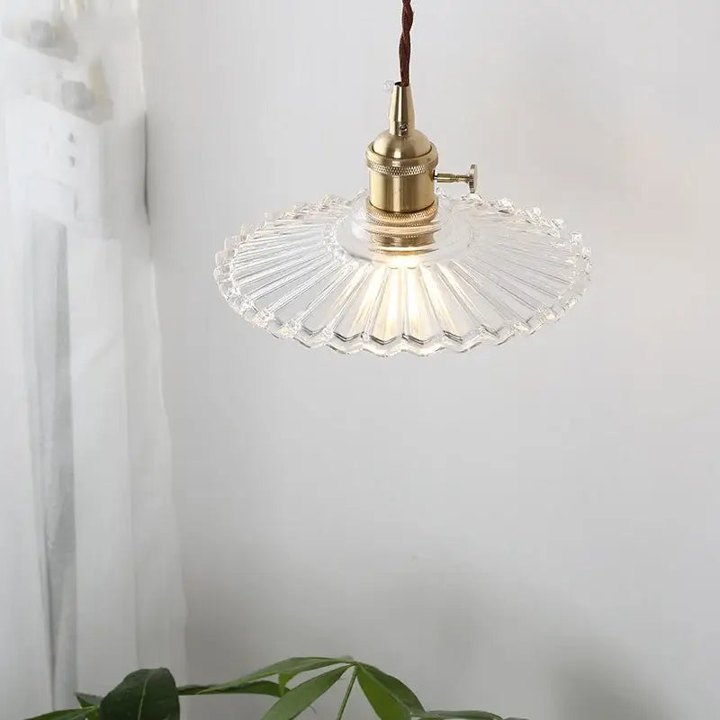 A clear fan-shaped glass copper led pendant lamp with brass fixture and brown cord for kitchen lighting