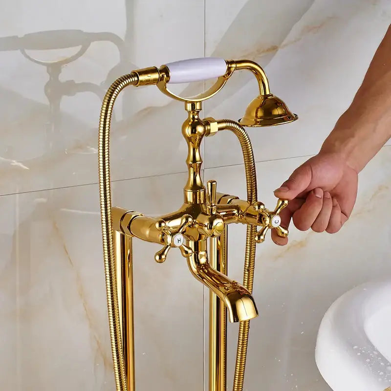 Vintage gold bath mixer tap with white ceramic handle cross-shaped knobs and handshower on flexible braided hoses