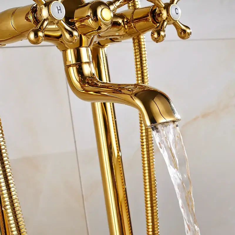 Vintage gold bath mixer tap in polished brass with cross handles marked h and c and flexible hose attachments