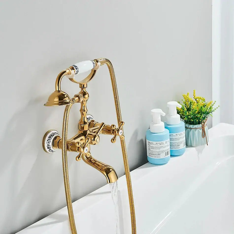 Vintage gold and black bathtub faucet with ornate gold finish and white ceramic handles featuring blue floral patterns