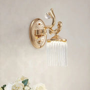 Vintage gold wall mounted light with clear pipe prisms and ornate curved arms for elegant bedroom lighting