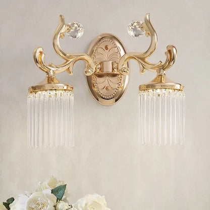 Vintage gold wall mounted light with ornate design clear pipe crystal accents and dangling glass prisms for bedroom