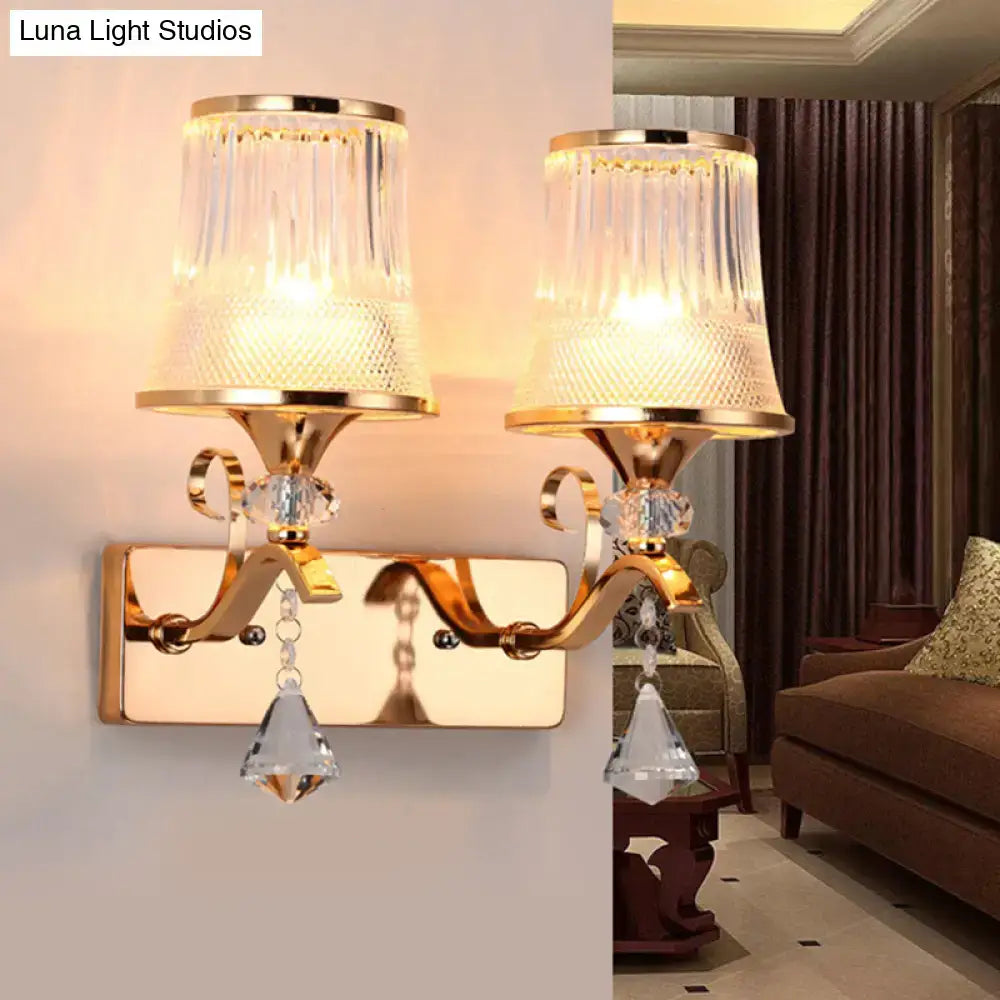 Vintage gold finish wall lamp with two clear glass fluted shades and dangling crystal accents for bedroom use