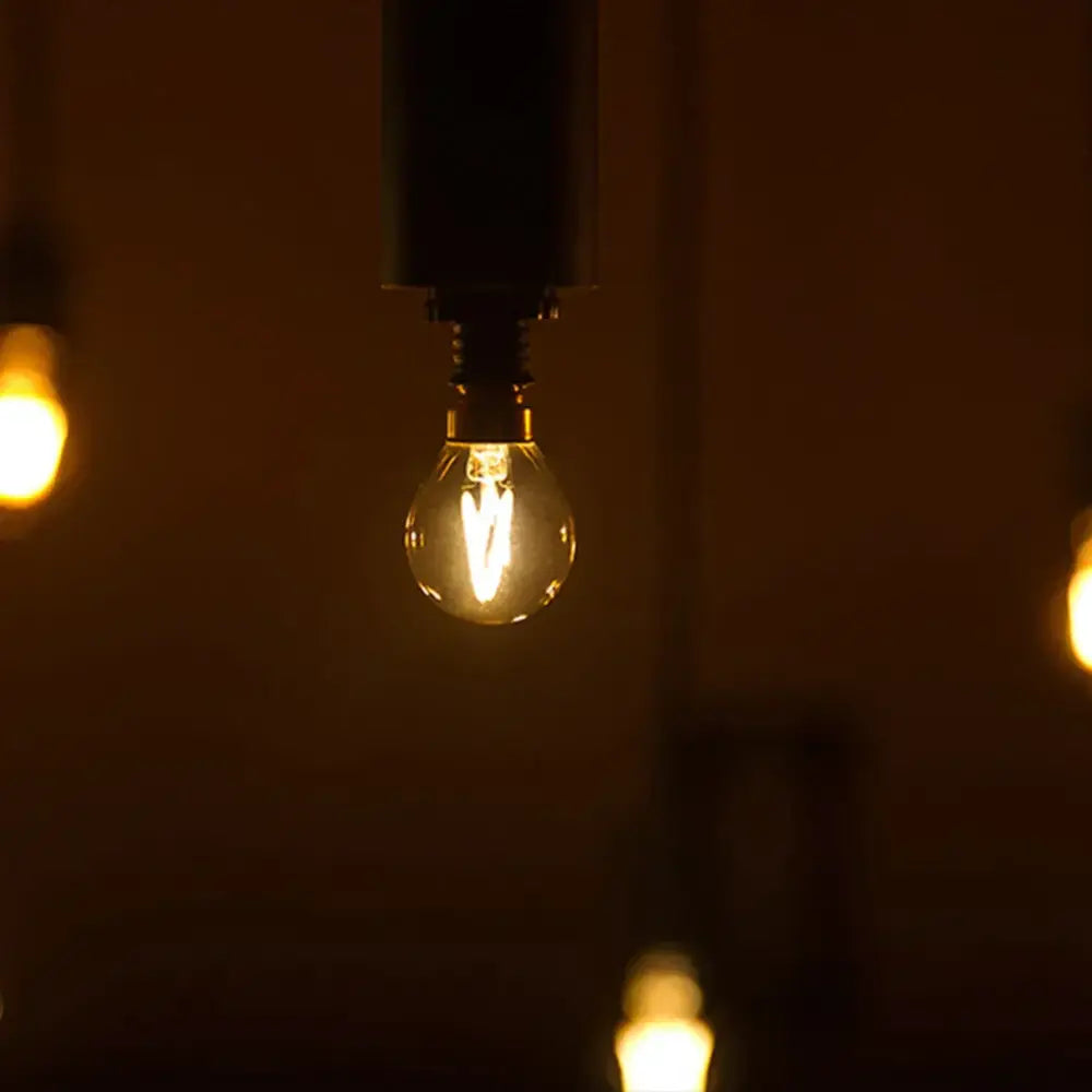 A glowing vintage gold glass led filament bulb with clear envelope and visible filament for outdoor camping light