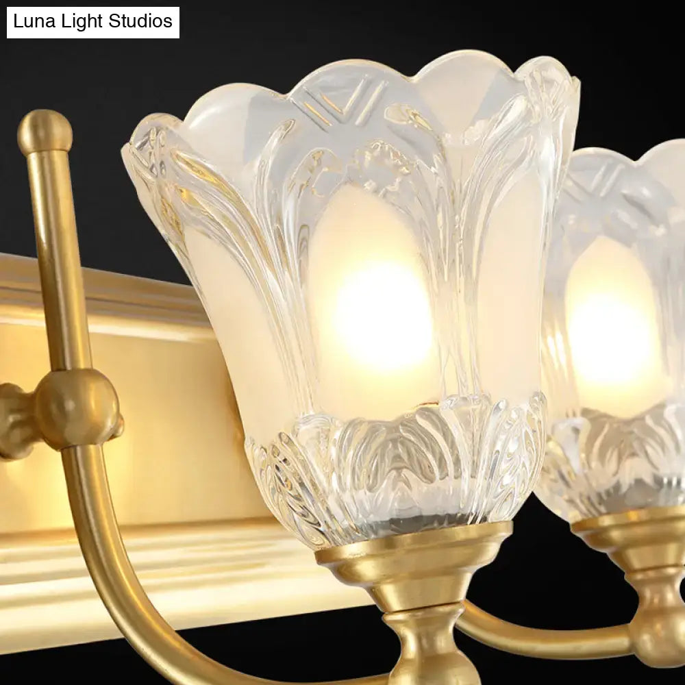 Vintage gold wall light featuring gold-finished metal and clear glass shade with intricately carved flower design