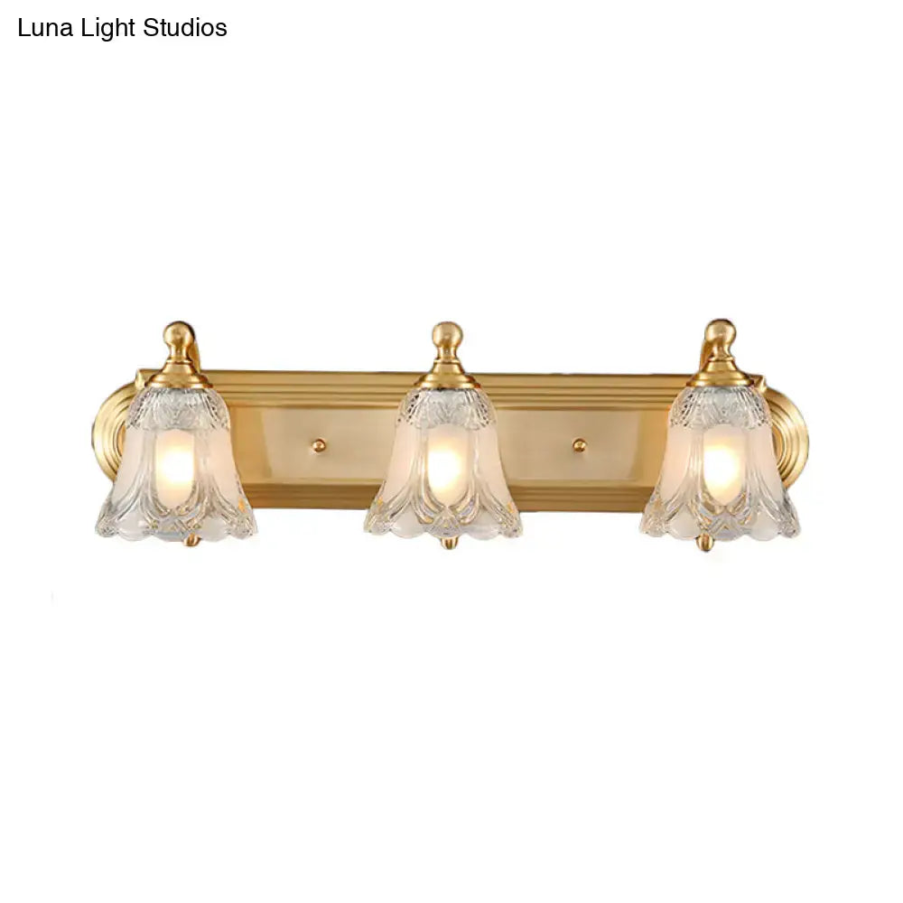 Vintage gold wall light with three clear glass shades featuring etched patterns for bathroom vanity lighting