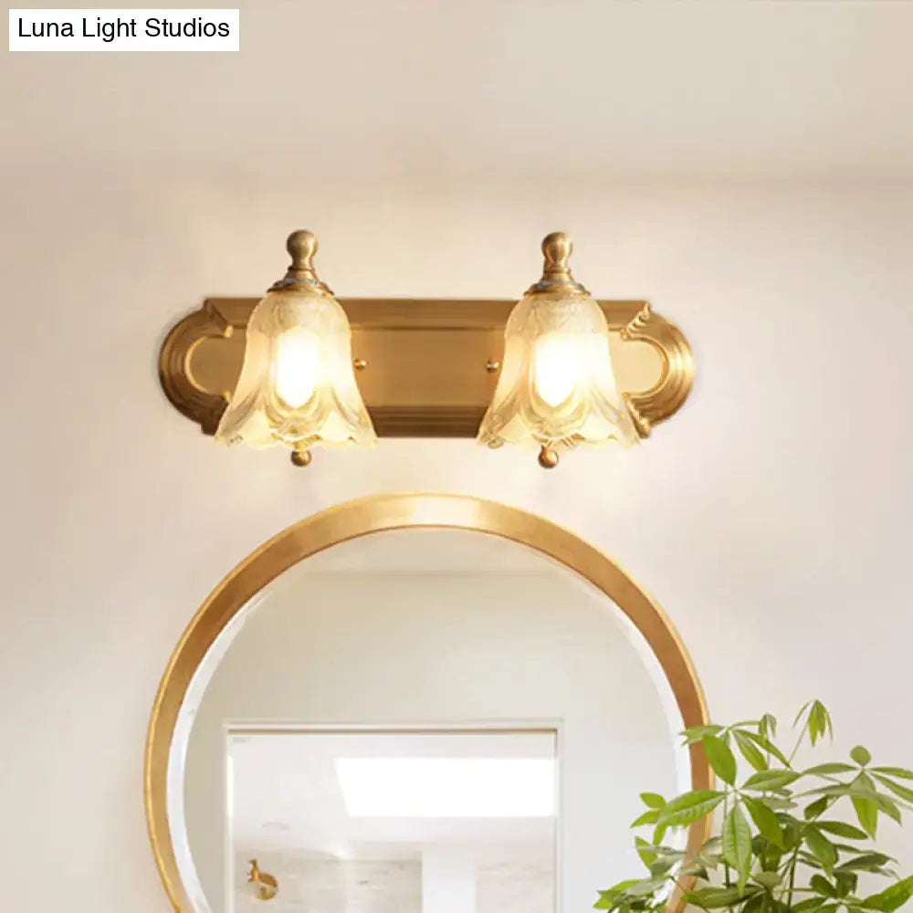Vintage gold wall light with clear glass shade featuring two bell-shaped clear glass shades for bathroom vanity lighting