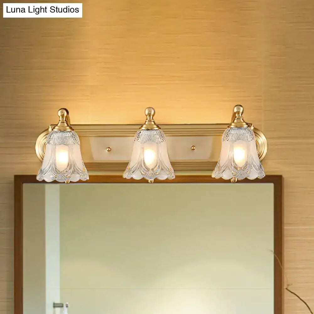 Three-light vintage gold wall light with brass finish and clear glass shade for bathroom vanity lighting