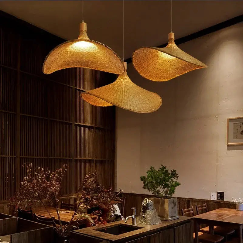 Three golden brown bamboo wicker chandelier pendant lights with woven design hang in a dining room setting
