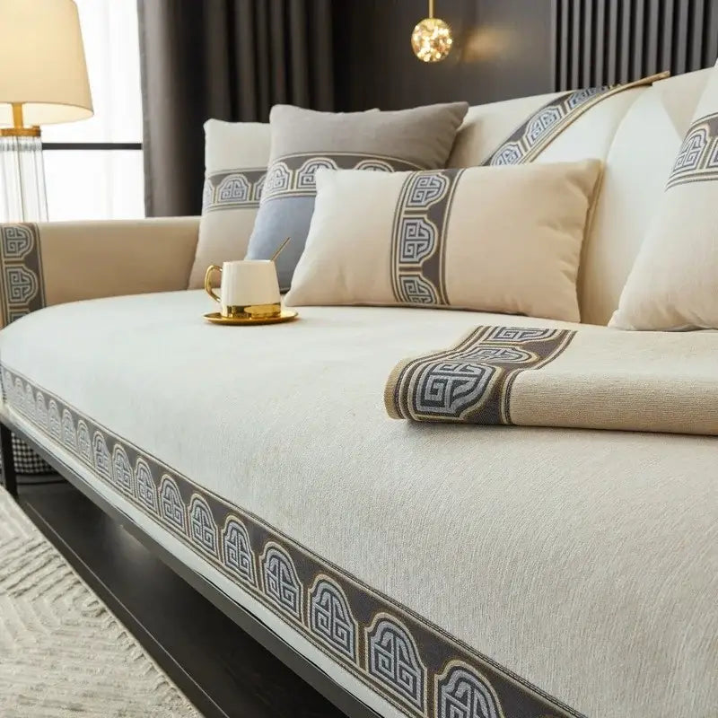 Beige chenille sofa cover with dark gray geometric pattern trim and blue and gold embroidery for living room
