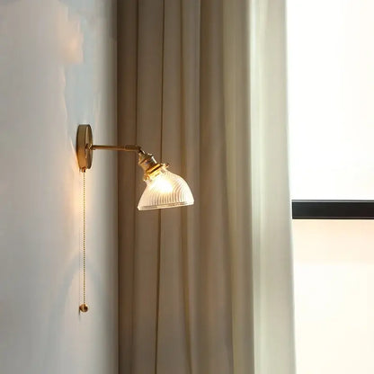 Antique brass-finished wall sconce with ribbed translucent green glass led shade and attached pull chain for bedroom use