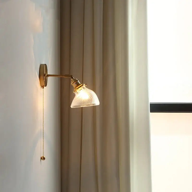 Antique brass-finished wall sconce with ribbed translucent green glass led shade and attached pull chain for bedroom use