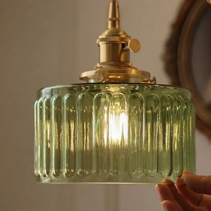 Vintage green glass pendant light featuring a ribbed shade and brass hardware ideal for dining room lighting