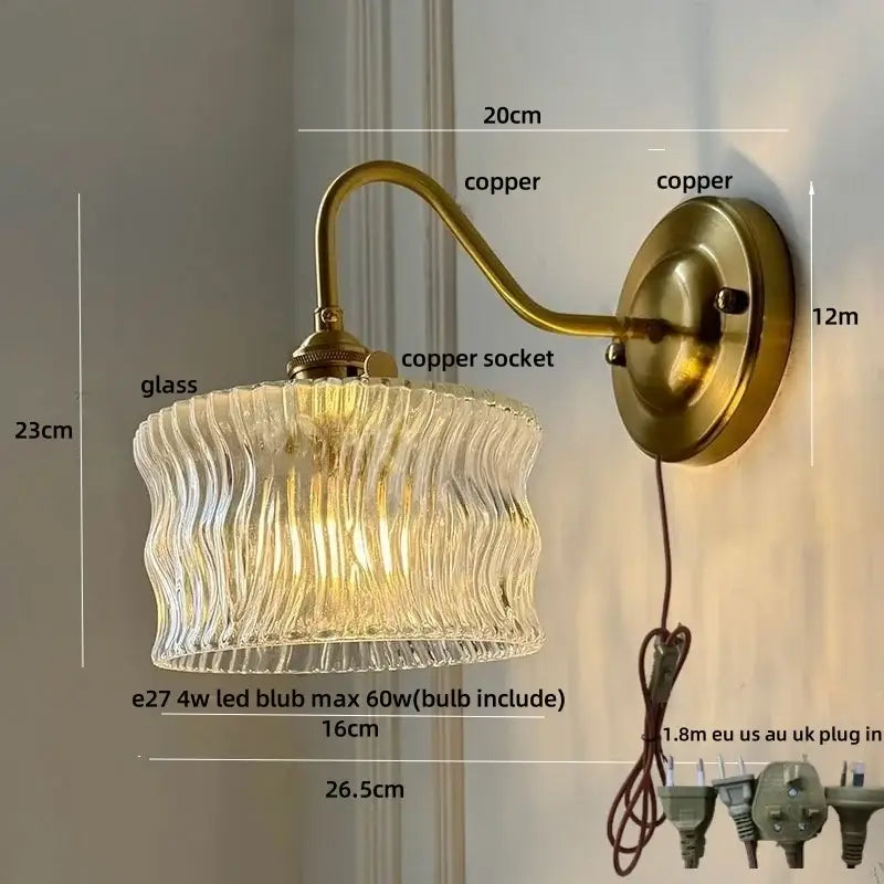 Vintage green glass wall light with brass-finished copper knob switch and textured clear glass shade with wavy ridges