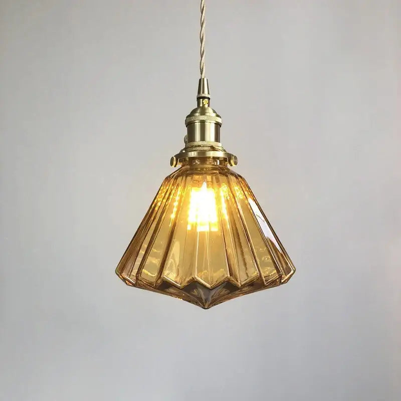 A warm amber glass pendant light with brass pumpkin led fixture and twisted cord for vintage decorbites style